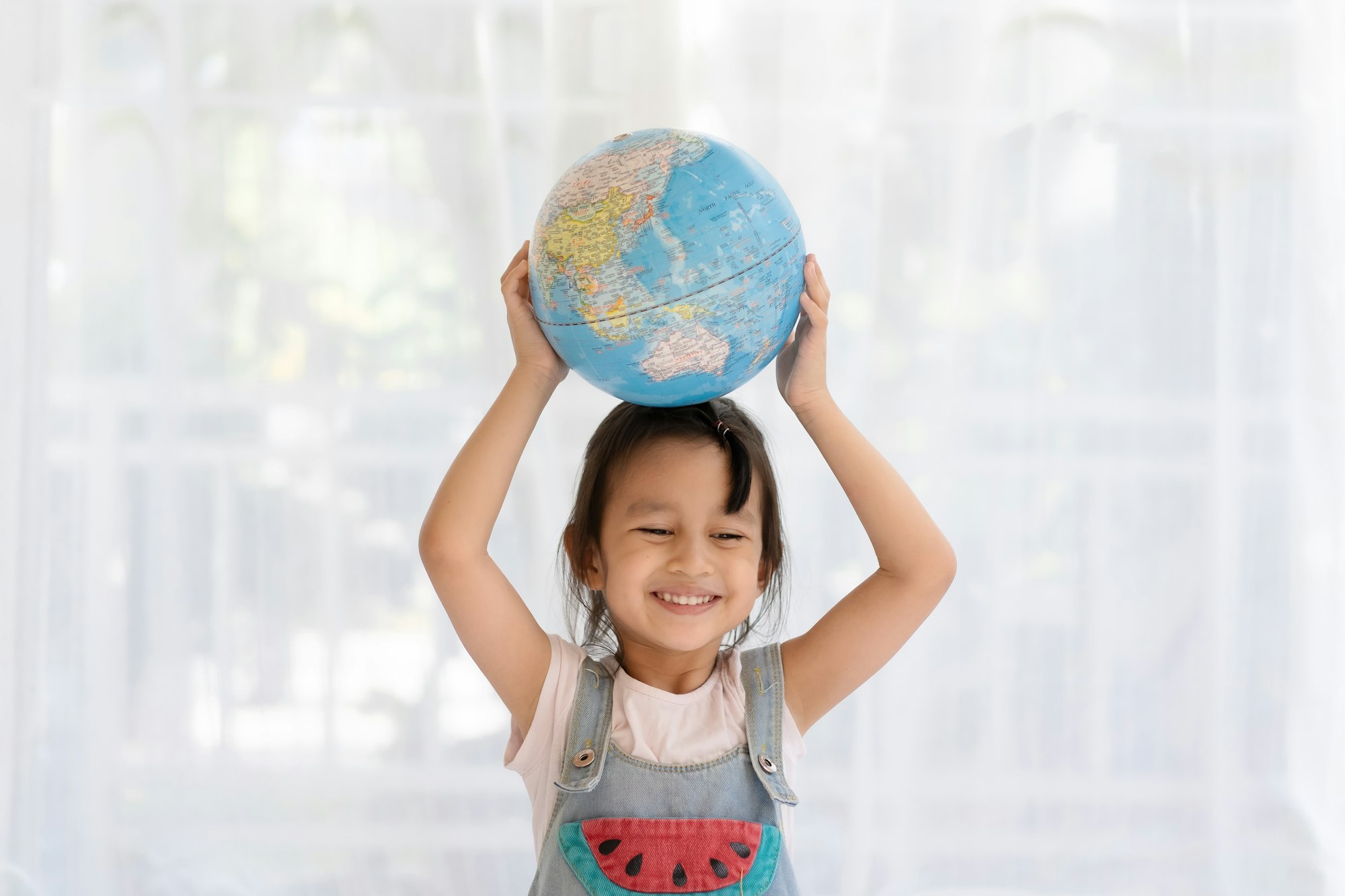 Happy aasian little girl is raising the globe model with love and concept of save the earth.